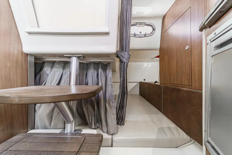 Slide: The Image of 2018 Boston Whaler 315 Conquest cabin interior with wood accents and seating area. - 38