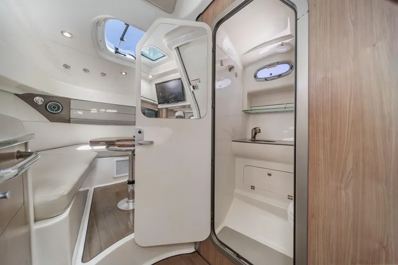 Slide: The Image of 2018 Boston Whaler 315 Conquest cabin interior with seating, table, and bathroom. - 39