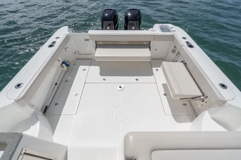 Slide: The Image of 2018 Boston Whaler 315 Conquest boat deck with seating and twin engines on water. - 9