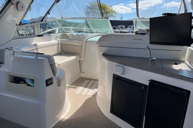 Slide: The Image of 2006 Rinker Fiesta Vee 342 boat interior with seating, kitchenette, and clear canopy. - 12