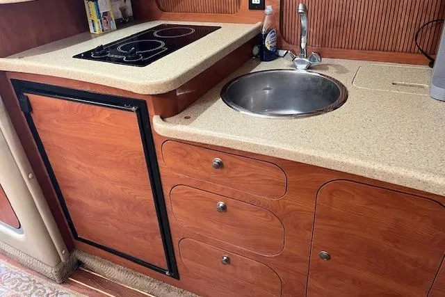 Slide: The Image of 2006 Rinker Fiesta Vee 342 boat kitchen with stove, sink, and wooden cabinetry. - 6