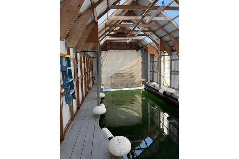 Slide: The Image of Interior of a 2006 BoatHouse, 18' x 40', with wooden beams and water. - 2
