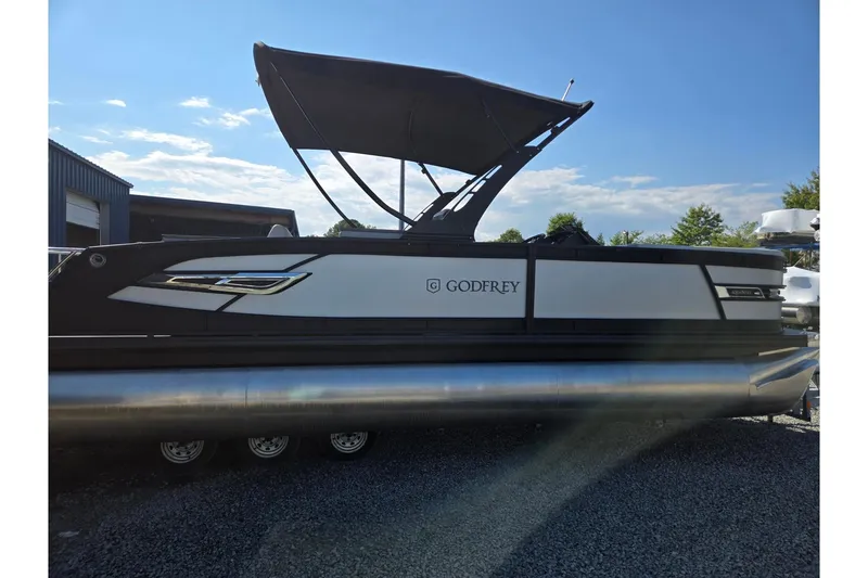 Slide: The Image of 2026 Godfrey AquaPatio 255 SFL pontoon boat with canopy, parked outdoors. - 7