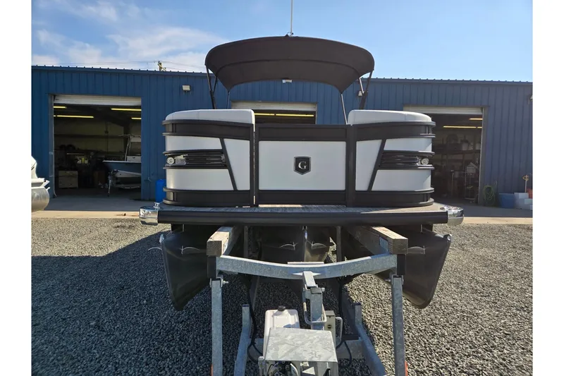Slide: The Image of 2026 Godfrey AquaPatio 255 SFL pontoon boat on trailer, parked outside blue building. - 8