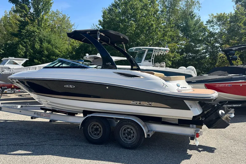 Slide: The Image of 2015 Sea Ray 230 SLX boat on trailer, parked outdoors with trees in background. - 3