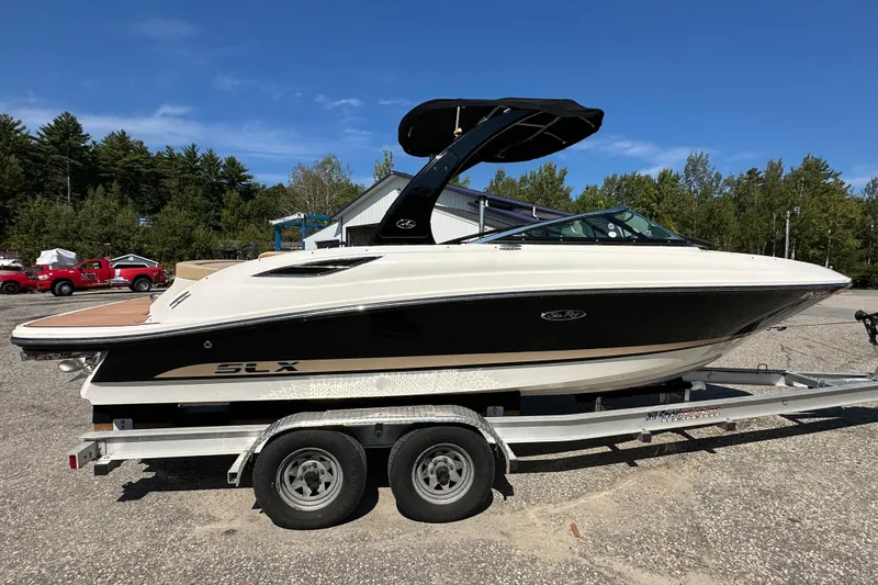 Slide: The Image of 2015 Sea Ray 230 SLX boat on trailer, parked outdoors under clear blue sky. - 6