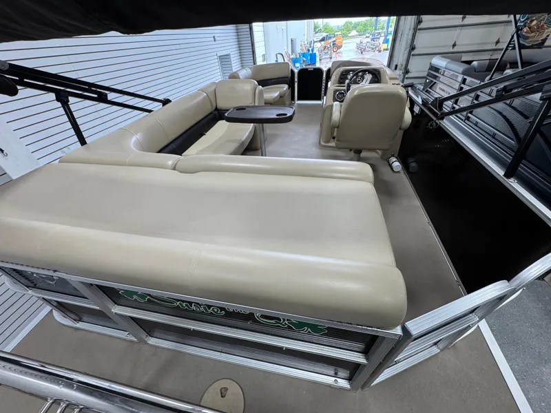 Slide: The Image of 2018 Manitou 21 Aurora LE Standard pontoon boat interior with beige seating and steering console. - 8
