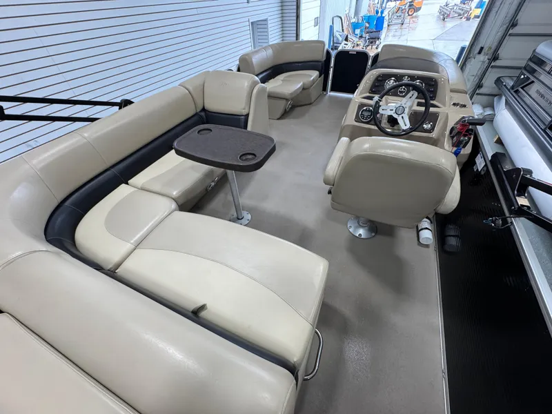 Slide: The Image of 2018 Manitou 21 Aurora LE Standard boat interior with beige seating and steering console. - 9