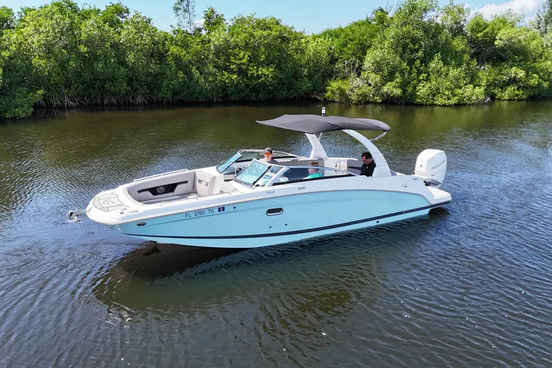 The Image of 2022 Four Winns HD8 boat cruising on a calm river with lush greenery. - 0