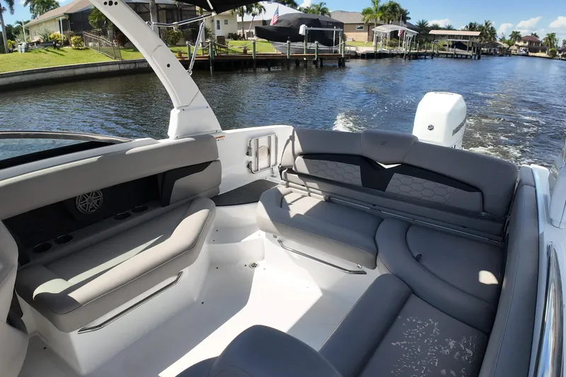 Slide: The Image of 2022 Four Winns HD8 boat interior with gray seating, cruising on a sunny waterway. - 17