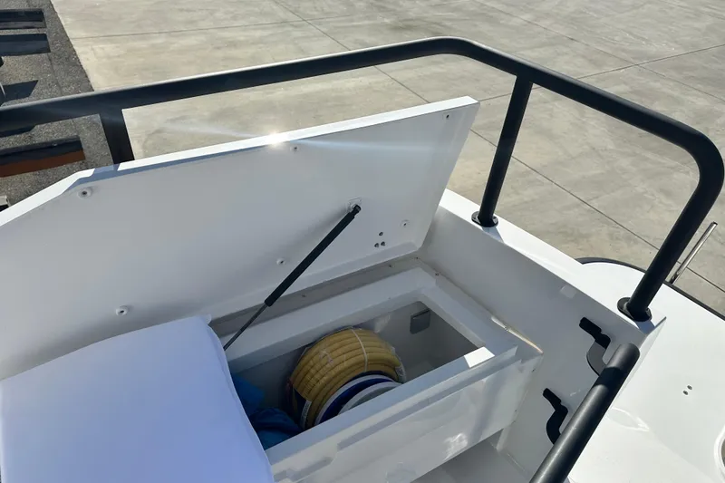 Slide: The Image of Open storage compartment on 2025 Sargo 31OB boat deck, featuring railing and clear sky. - 17