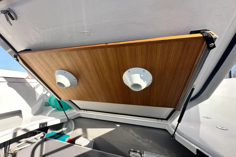 Slide: The Image of Open storage compartment in 2025 Sargo 31OB boat, featuring wooden panel and ventilation outlets. - 20