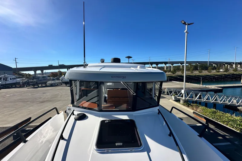 Slide: The Image of 2025 Sargo 31OB boat interior with open door, outdoor seating, and wooded background. - 5