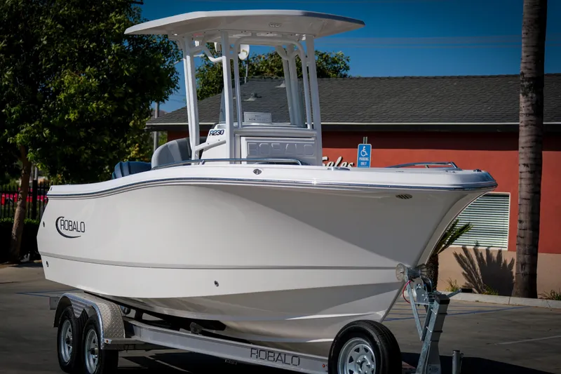 The Image of 2025 Robalo R230 Center Console boat on trailer, parked outdoors. - 1