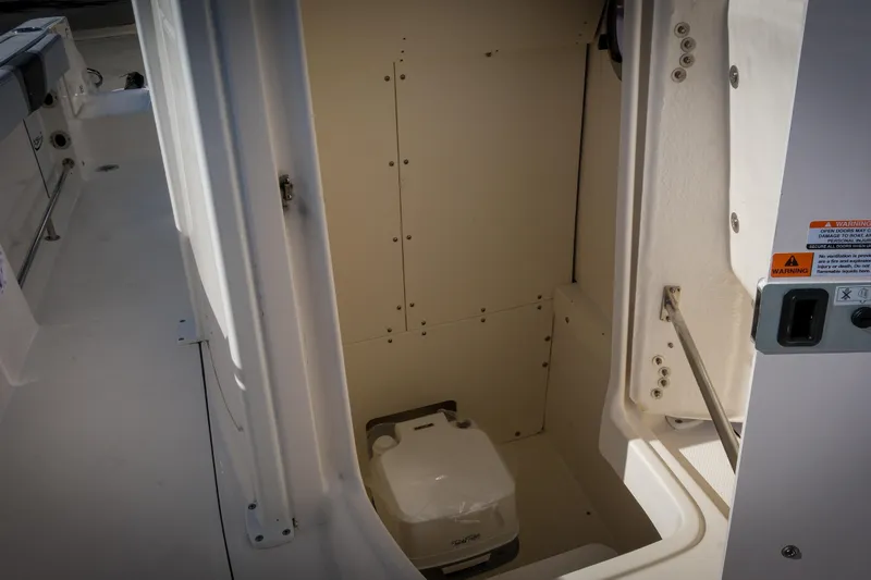 Slide: The Image of 2025 Robalo R230 Center Console boat interior with storage compartment and portable toilet. - 13
