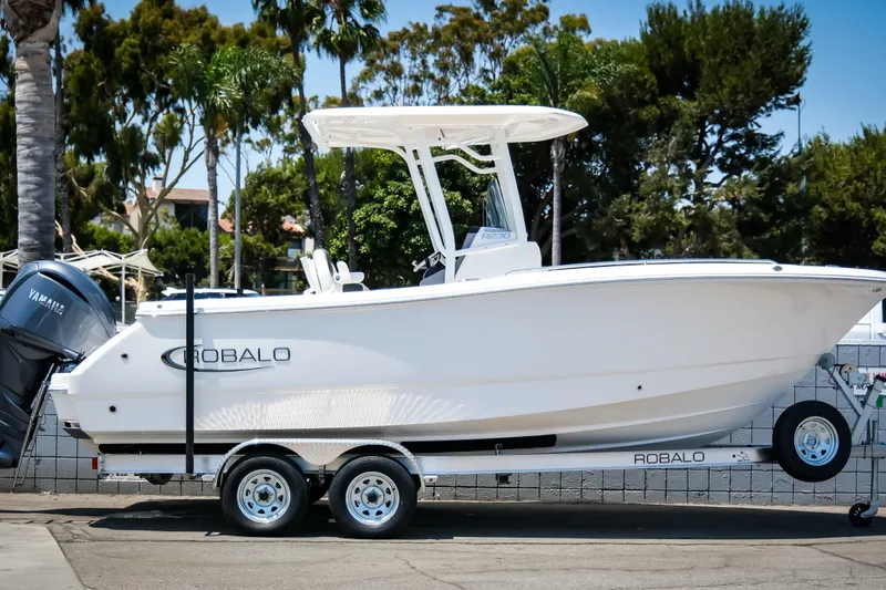 Slide: The Image of 2025 Robalo R230 Center Console boat on trailer, parked outdoors. - 12