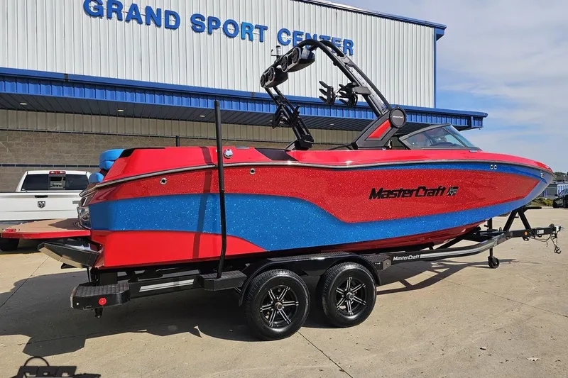 Slide: The Image of 2022 MasterCraft XT24 boat in red and blue, parked at Grand Sport Center. - 10
