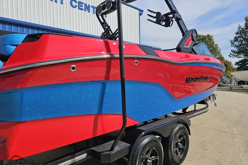 Slide: The Image of 2022 MasterCraft XT24 boat in vibrant red and blue, displayed outdoors. - 11