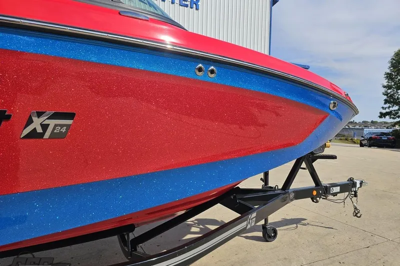 Slide: The Image of 2022 MasterCraft XT24 boat with red and blue glitter finish on a trailer. - 12