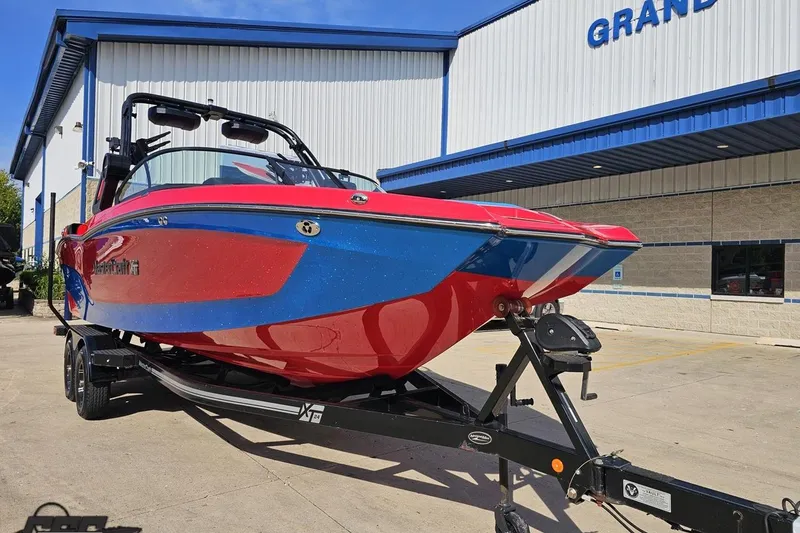 Slide: The Image of 2022 MasterCraft XT24 boat in red and blue on a trailer outside a building. - 14