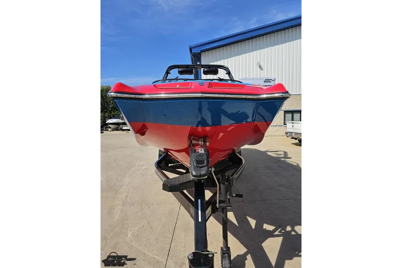 Slide: The Image of 2022 MasterCraft XT24 boat on trailer, red and blue exterior, parked outdoors. - 15