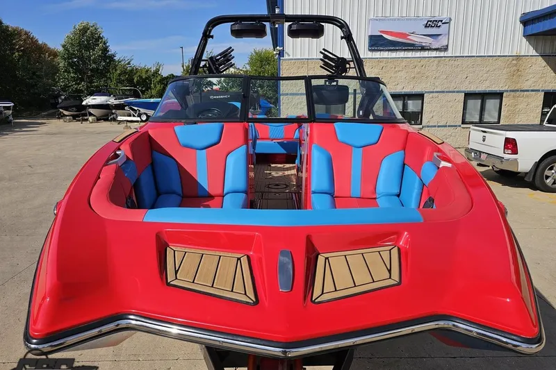 Slide: The Image of 2022 MasterCraft XT24 boat with vibrant red and blue seating, parked outdoors. - 16