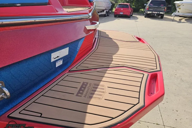 Slide: The Image of 2022 MasterCraft XT24 boat with custom teak swim platform in a parking lot. - 26