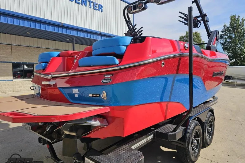 Slide: The Image of 2022 MasterCraft XT24 boat in vibrant red and blue, parked on a trailer. - 29