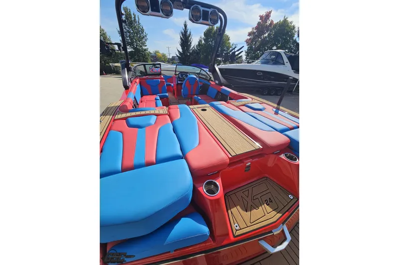 Slide: The Image of 2022 MasterCraft XT24 boat with vibrant red and blue seating, outdoor setting. - 34