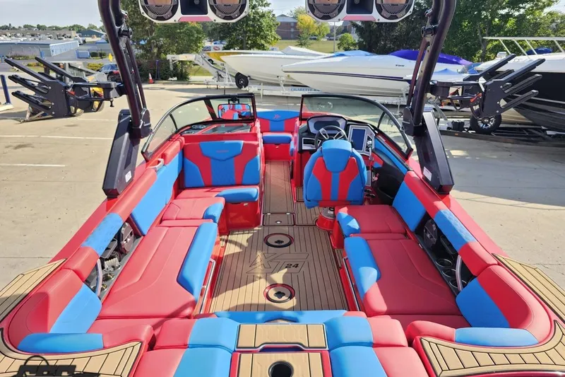 Slide: The Image of 2022 MasterCraft XT24 boat with vibrant red and blue interior, docked outdoors. - 36