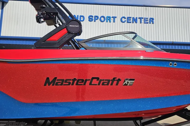 Slide: The Image of 2022 MasterCraft XT24 boat in red and blue, displayed at a sports center. - 4