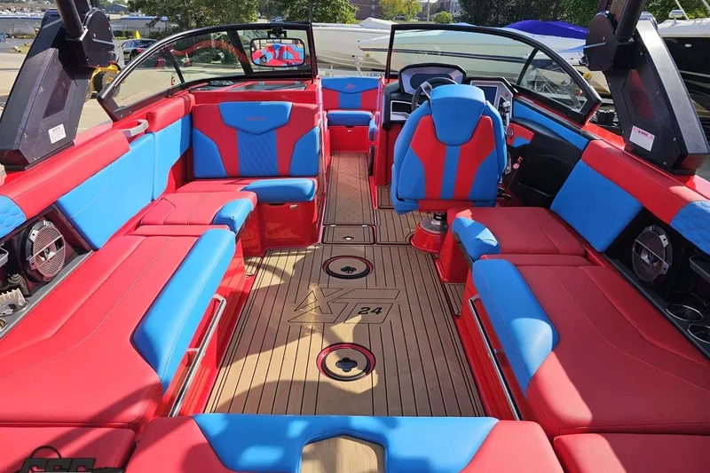 Slide: The Image of 2022 MasterCraft XT24 boat interior with vibrant red and blue seating, wood flooring. - 47