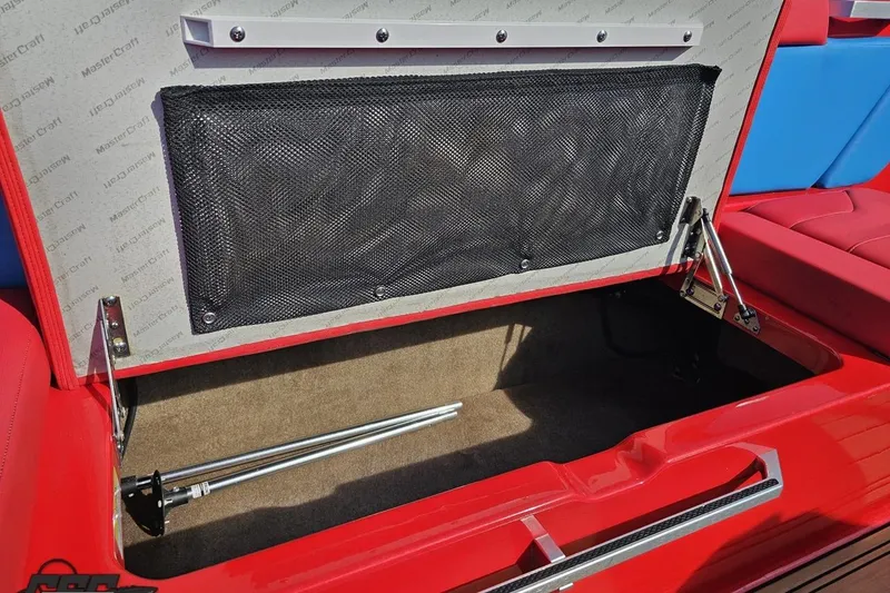 Slide: The Image of 2022 MasterCraft XT24 boat storage compartment with red upholstery and hydraulic lift. - 49