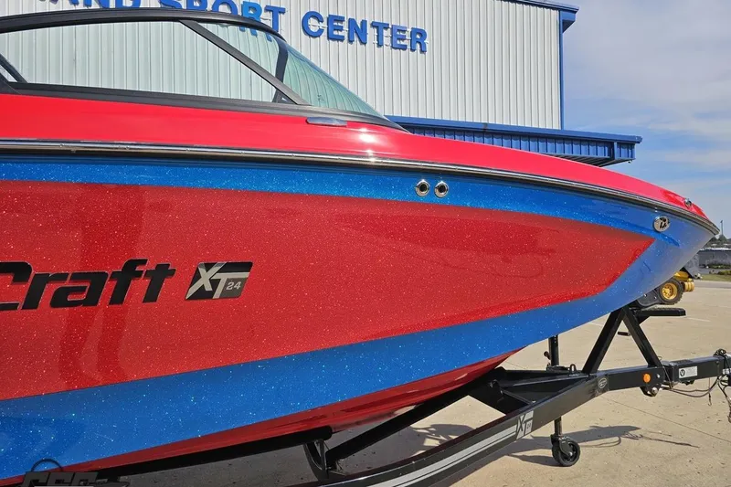Slide: The Image of 2022 MasterCraft XT24 boat with red and blue glitter finish on trailer. - 5