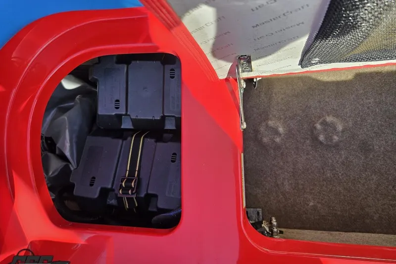 Slide: The Image of 2022 MasterCraft XT24 boat storage compartment with battery boxes and carpeted interior. - 50