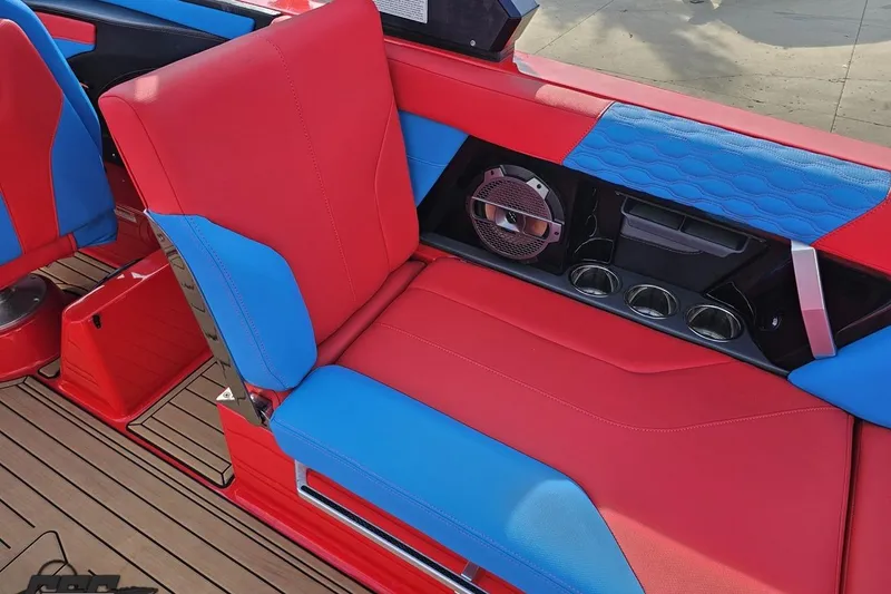 Slide: The Image of 2022 MasterCraft XT24 interior with red and blue seating, speaker, and cup holders. - 57