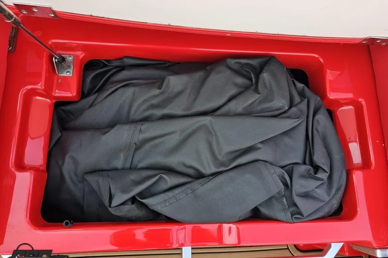 Slide: The Image of Red storage compartment in 2022 MasterCraft XT24 boat with black cover inside. - 58