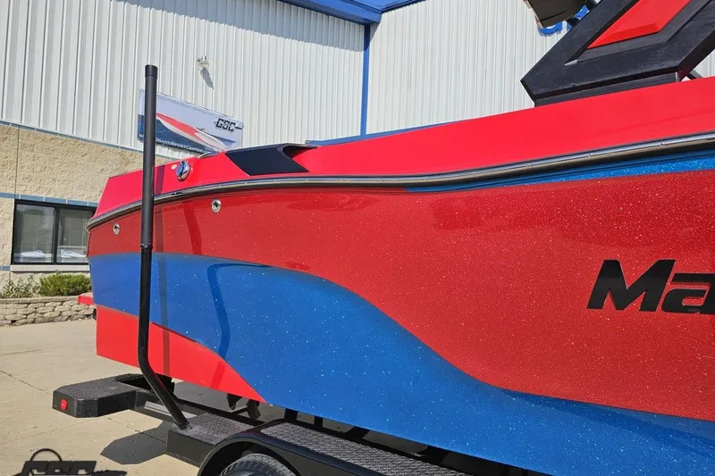 Slide: The Image of 2022 MasterCraft XT24 boat with vibrant red and blue design, parked outside a building. - 6