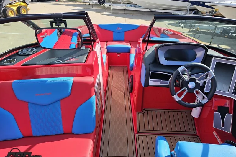 Slide: The Image of 2022 MasterCraft XT24 boat interior with red and blue seating, modern dashboard, and steering wheel. - 61