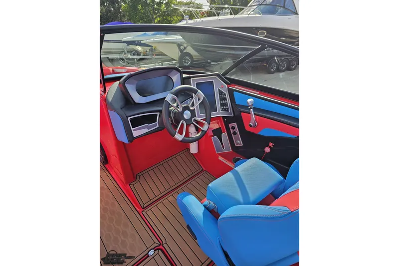 Slide: The Image of 2022 MasterCraft XT24 boat interior with vibrant red and blue seating and modern dashboard. - 63