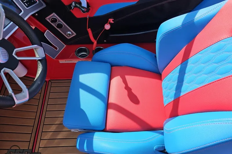 Slide: The Image of 2022 MasterCraft XT24 interior with vibrant red and blue seating, modern steering wheel, and wood-style flooring. - 65