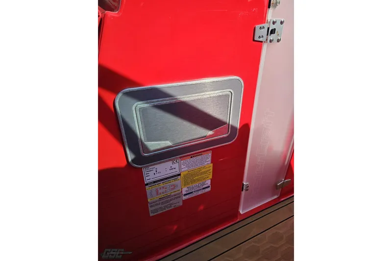 Slide: The Image of Red 2022 MasterCraft XT24 boat detail with safety labels and metal latch. - 76