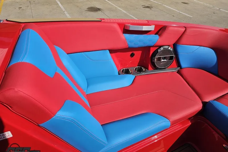 Slide: The Image of 2022 MasterCraft XT24 boat interior with red and blue seating, cup holders, and speaker. - 86
