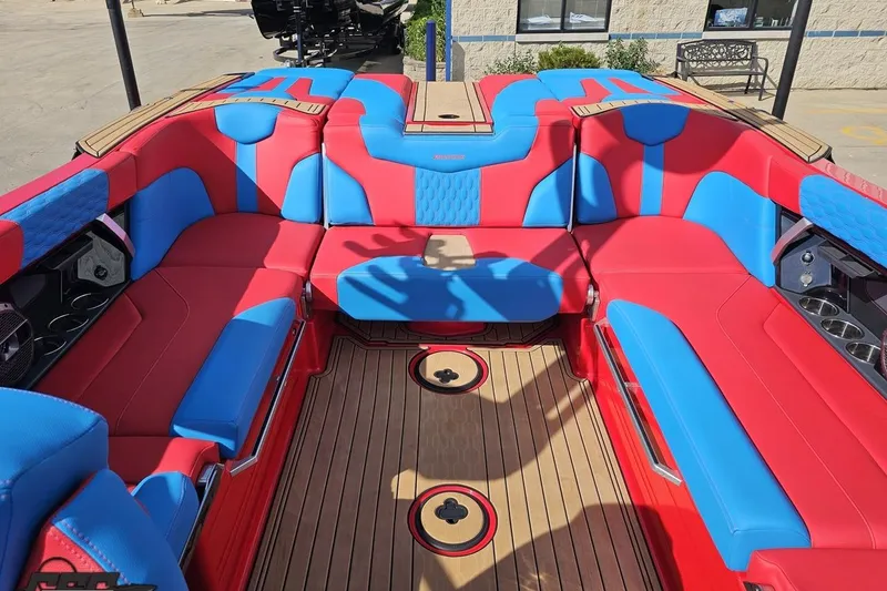 Slide: The Image of 2022 MasterCraft XT24 boat interior with vibrant red and blue seating, wooden flooring. - 94