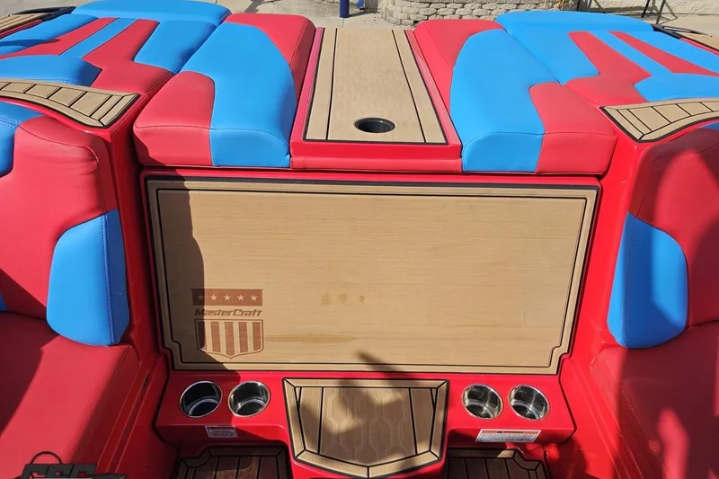 Slide: The Image of 2022 MasterCraft XT24 boat interior with red and blue seating and cup holders. - 97