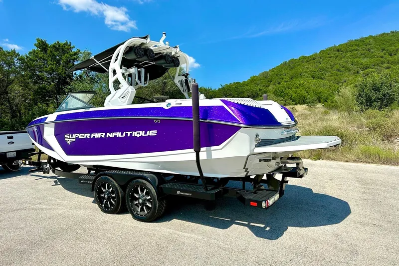 Slide: The Image of 2017 Nautique Super Air Nautique G23 boat on trailer, purple and white design, outdoors. - 20