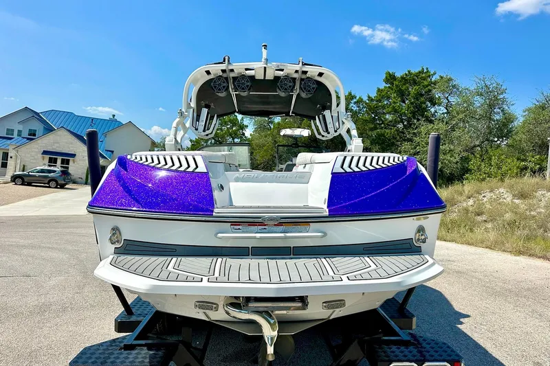 Slide: The Image of 2017 Nautique Super Air Nautique G23 boat with vibrant purple accents, parked outdoors. - 21