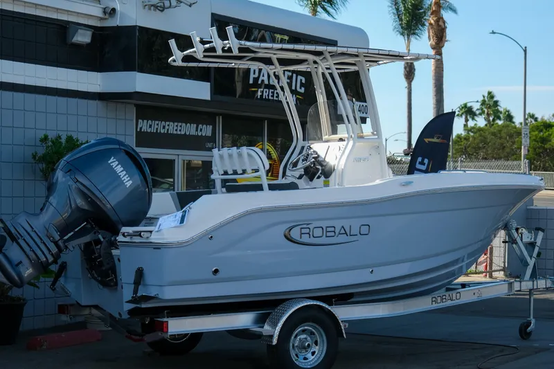 Slide: The Image of 2025 Robalo R180 Center Console boat on trailer with Yamaha engine, parked outside dealership. - 4