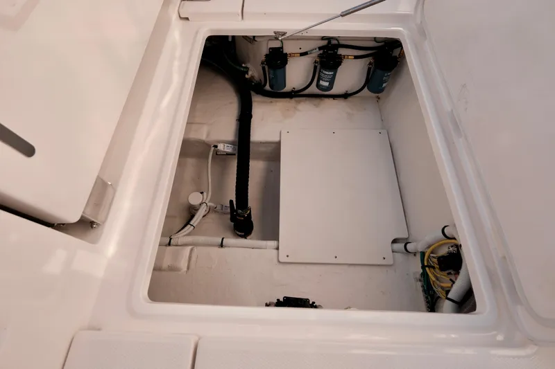 Slide: The Image of 2024 Robalo R360 Center Console boat storage compartment with visible wiring and components. - 23