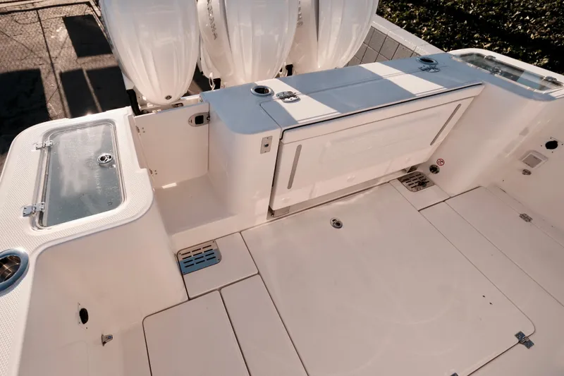 Slide: The Image of 2024 Robalo R360 Center Console boat deck with storage compartments and triple outboard engines. - 25